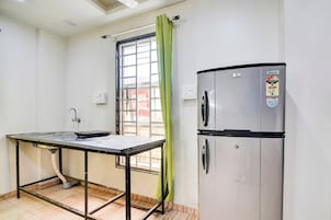 Uma pequena cozinha compacta com geladeira de aço inoxidável, pia e mesa.
