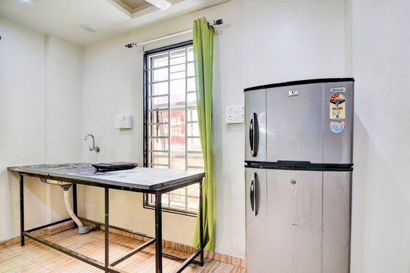 A small kitchenette with a stainless steel refrigerator, a sink, and a table. - Super Hotel O Pioneer (Paud)