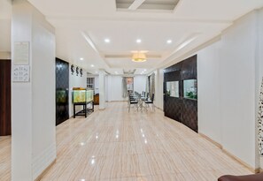 A spacious hallway with a tiled floor, a dining area with tables and chairs, and a ceiling with recessed lighting. - Super Hotel O Pioneer (Paud)