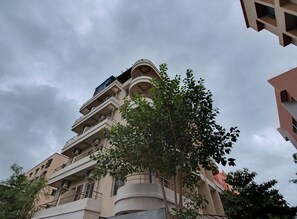 A multi-story building with balconies and a tree in the foreground. - Super Hotel O Pioneer (Paud)