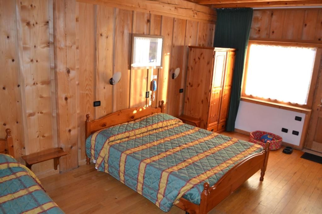 A wooden-paneled room with a bed, a bench, a wardrobe, and a window.