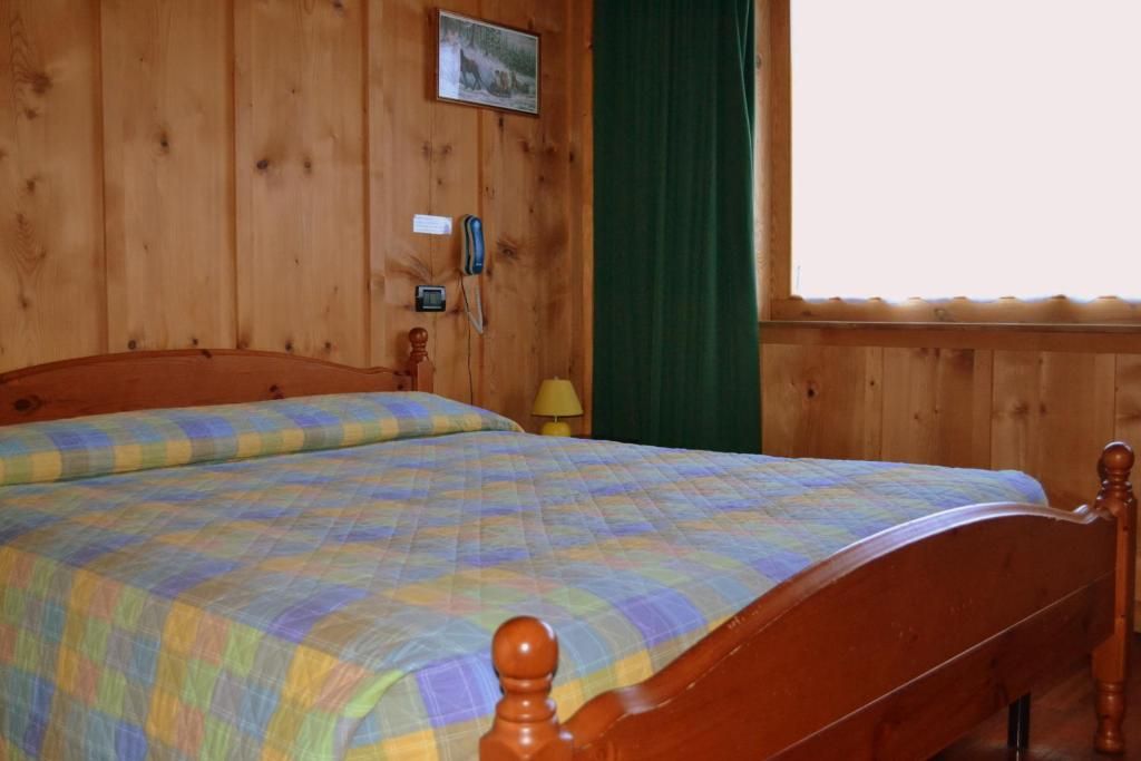 A wooden-paneled room with a bed, a wall-mounted telephone, and a picture.
