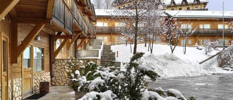Un edificio de madera con balcón, paredes de piedra y un paisaje cubierto de nieve.