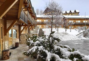 A wooden building with a balcony, stone walls, and a snow-covered landscape.