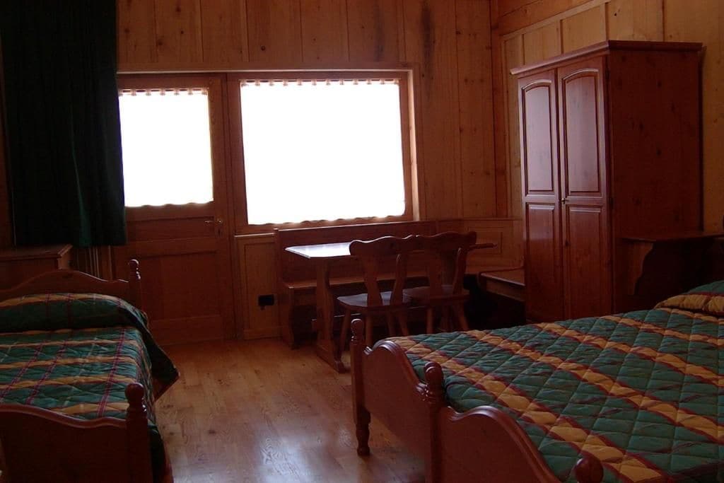 Quarto de madeira com duas camas, uma mesa e uma cadeira.