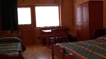 Una stanza in legno con due letti, un tavolo e una sedia.