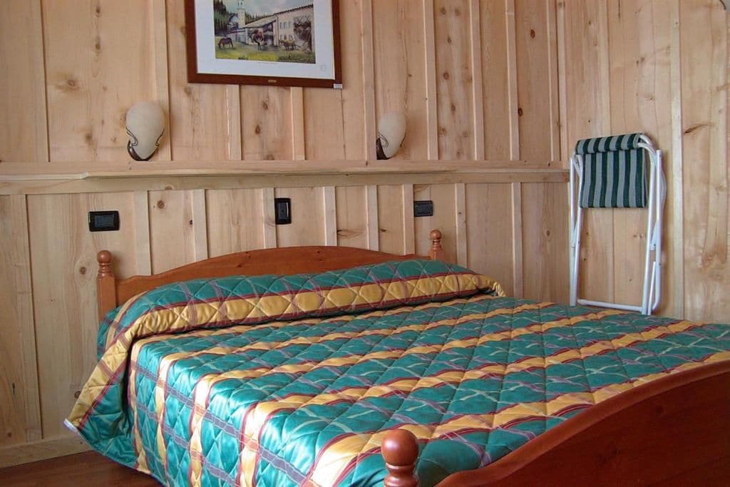 Ein Zimmer mit Holzwandverkleidung, einem Bett, einem Bild an der Wand und einem Handtuchhalter.