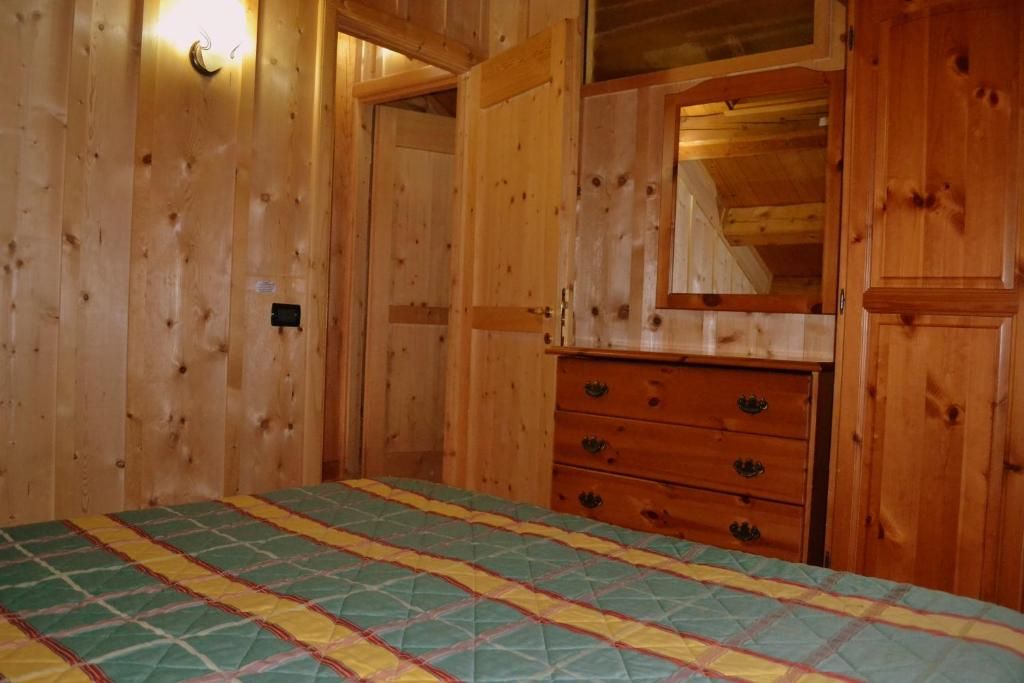 Une pièce en bois avec un lit, une commode et un miroir.