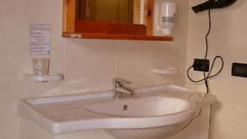 A bathroom with a white sink, wooden cabinet, and a mirror with a wooden frame.