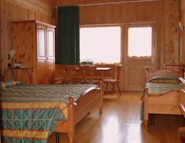Una habitación de madera con dos camas, una mesa y sillas.