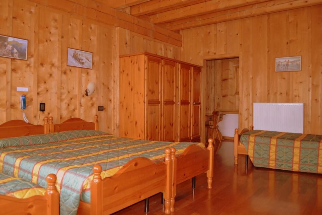 Una habitación con paneles de madera, dos camas de madera, un armario y un radiador.