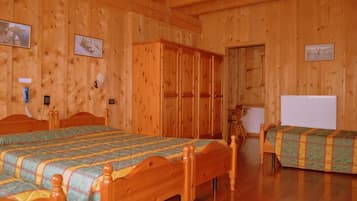 Una habitación con paneles de madera, dos camas de madera, un armario y un radiador.