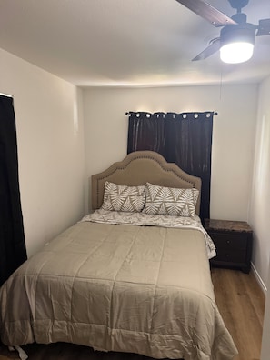 A bedroom with a bed, a nightstand, a ceiling fan, and a window with curtains. - Beautiful 4-bedroom house in enchanting West Orange with AC (West Orange)