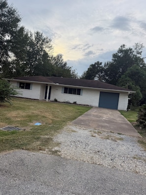 A single-story house with a garage, a driveway, and a grassy yard. - Beautiful 4-bedroom house in enchanting West Orange with AC (West Orange)