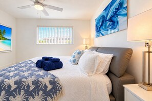 A bedroom with a bed, a ceiling fan, a window with blinds, a painting, and a lamp. - Private Pool | BBQ | Outdoor Dining (Hollywood)