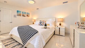 A hotel room with a bed, bedside tables, a nightstand, a dresser, and wall art. - Private Pool | BBQ | Outdoor Dining (Hollywood)