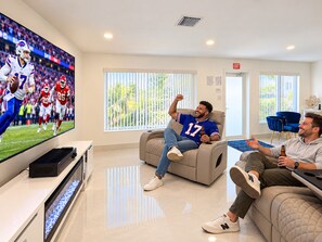 A modern living room with a flat-screen TV, comfortable seating, and a view of the outdoors. - Private Pool | BBQ | Outdoor Dining (Hollywood)