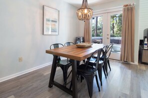 A dining area with a wooden table, black chairs, a chandelier, and a view through a glass door. - 3 Bedroom Townhome- With Resort Access (Edisto Island)