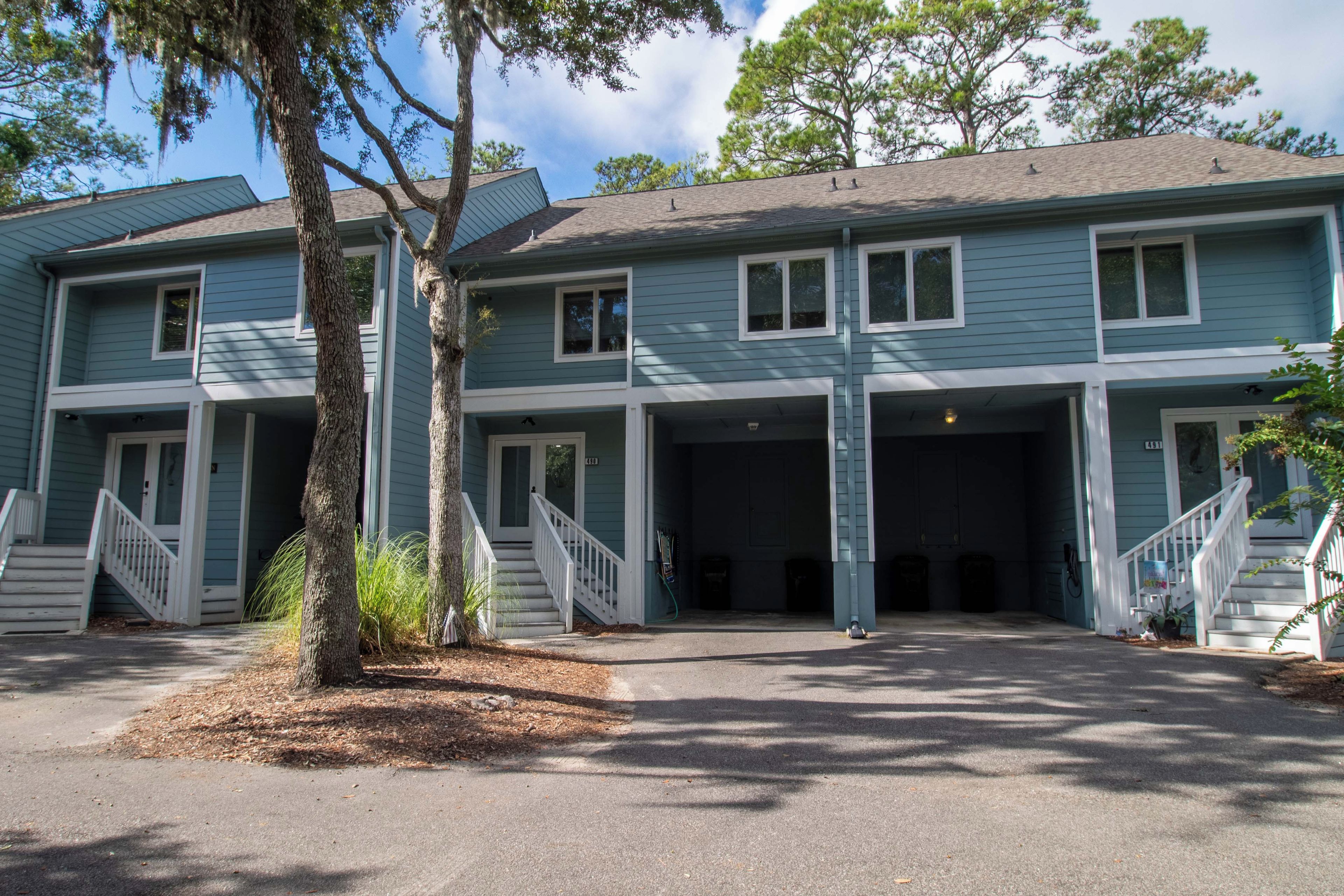 A two-story building with a central entrance, a covered parking area, and a staircase leading to the entrance.