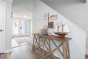 A hallway with a wooden console table, a small sailboat model, and nautical-themed wall decor. - 3 Bedroom Townhome- With Resort Access (Edisto Island)