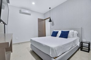 A modern bedroom with a bed, bedside table, and a hanging lamp. - Distrito Corazón: 1BR, 2 Baths & Rooftop Pool (Playa del Carmen)