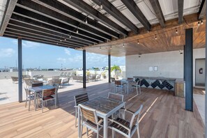 Un espace extérieur aménagé en terrasse, avec des tables et des chaises, un bar et une vue sur le paysage urbain.