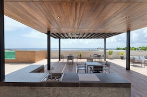 Ein überdachter Außenbereich mit Pool, Sitzgelegenheiten und Blick auf das Meer.