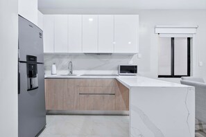 Eine moderne Küche mit weißen Schränken, einer Marmorarbeitsplatte und einem eingebauten Backofen.