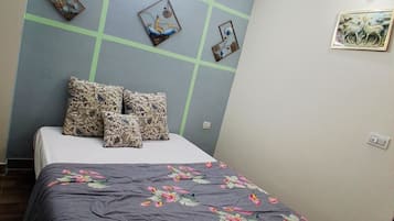 Una camera da letto con un letto, una coperta a fiori, decorazioni murali e una ventola a soffitto.