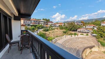 A balcony with a view of a residential area and an ancient amphitheater.