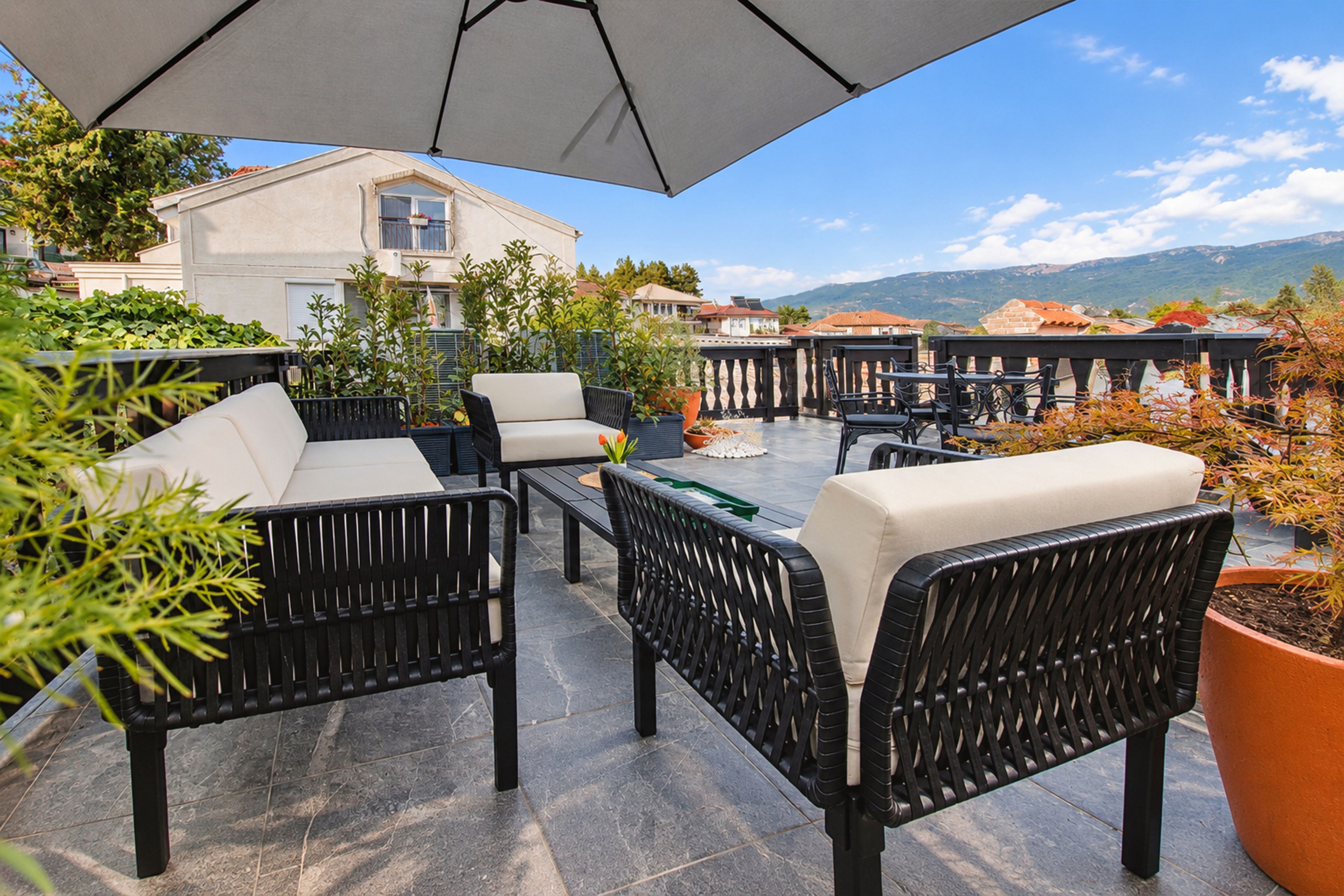 An outdoor patio with wicker furniture, a table, and a large umbrella.