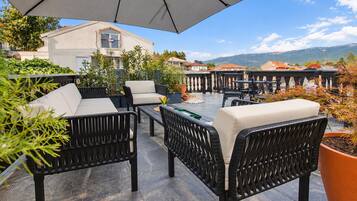 An outdoor patio with wicker furniture, a table, and a large umbrella.
