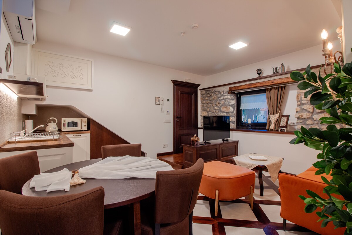 A modern living room with a dining area, a kitchen, and a stone accent wall.