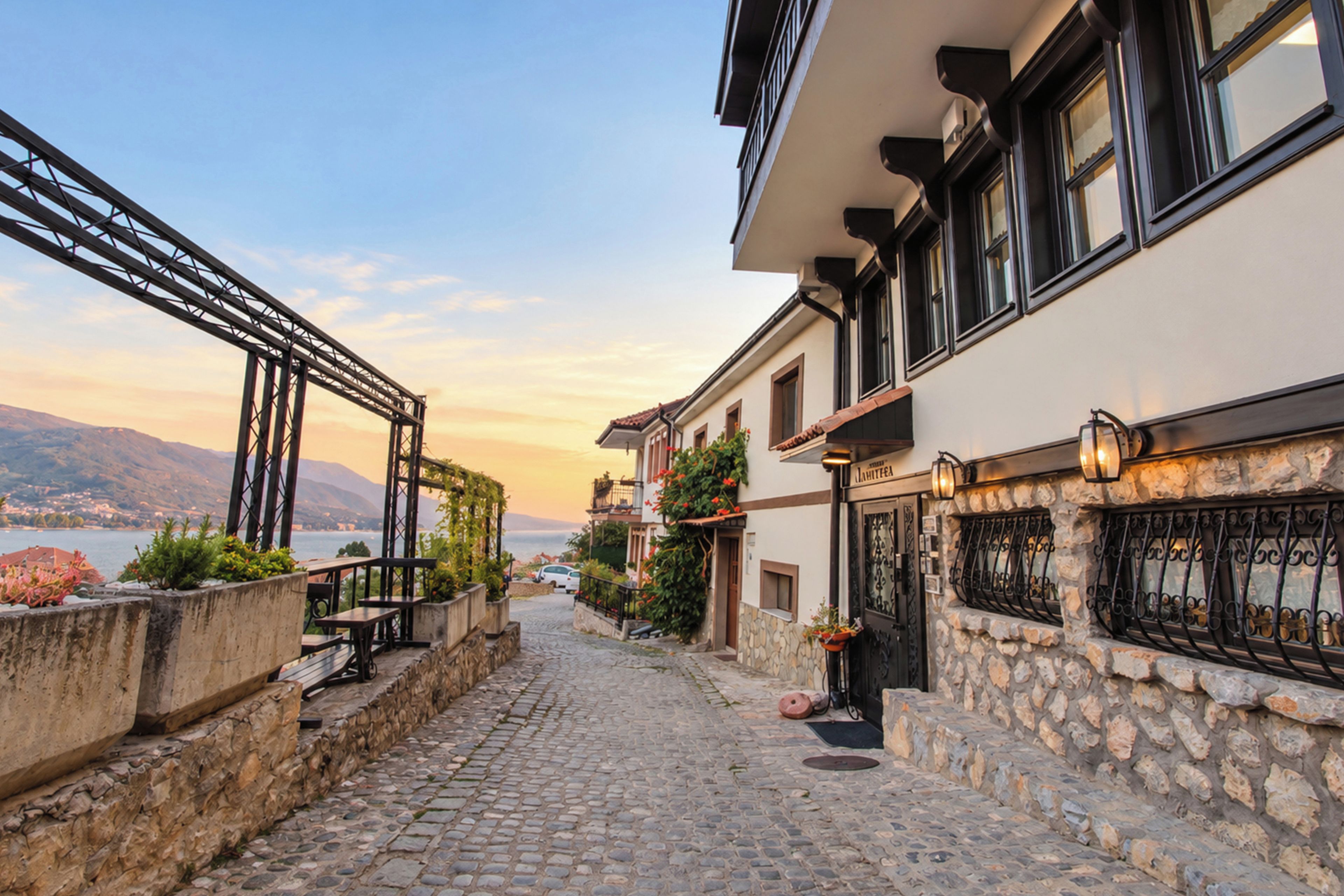 Eine Kopfsteinpflasterstraße führt zu einem Gebäude mit einer steinernen Fassade, einem Balkon und Blick auf das Meer.