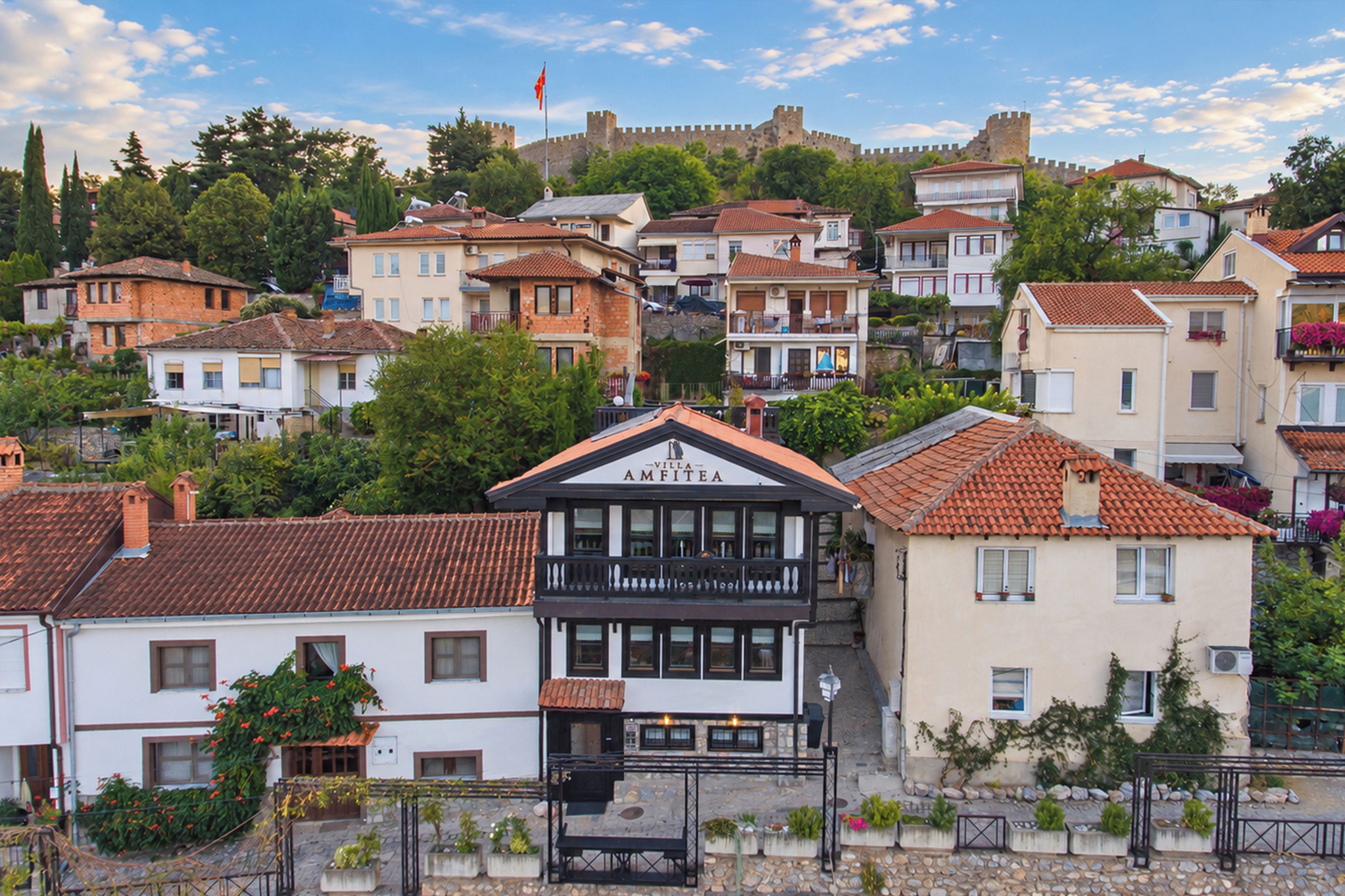 A building with a sign that reads 'Villa Amfitea' surrounded by residential buildings with red-tiled roofs.