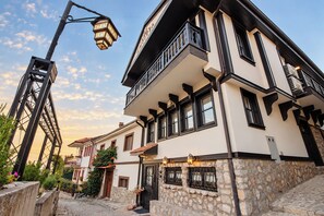 A building with a stone facade, multiple windows, and a balcony. - Villa Amfitea (Ohrid)