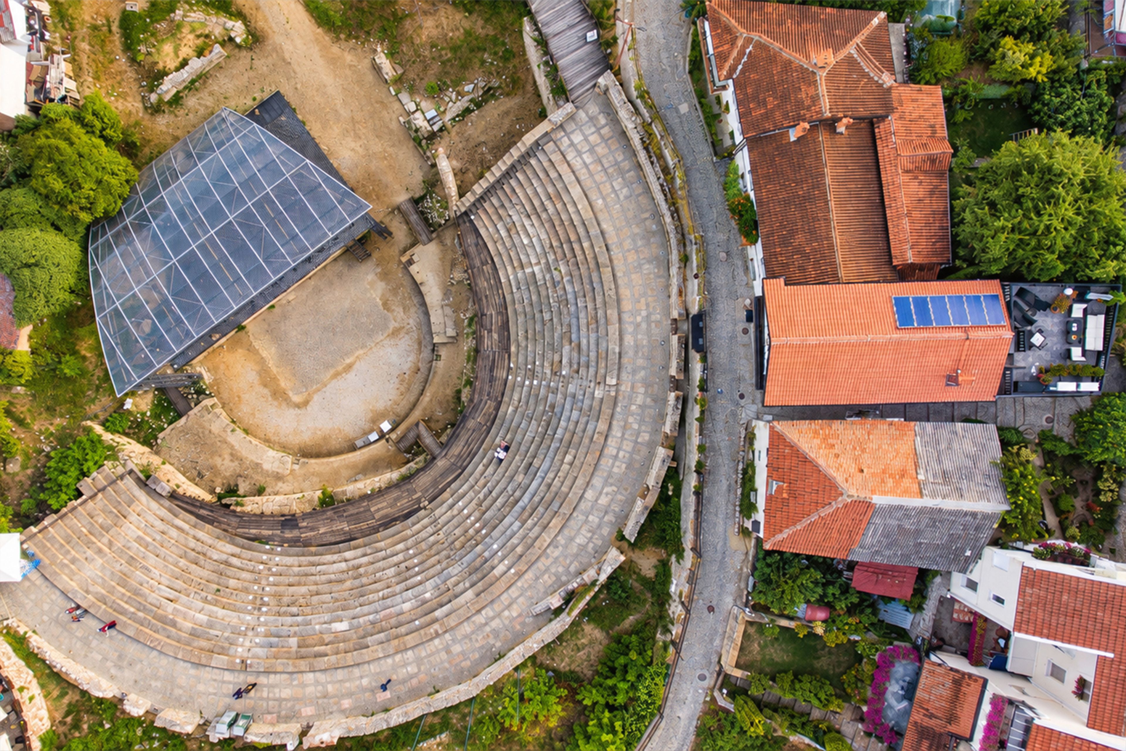 Un anfiteatro con asientos escalonados, un panel solar y edificios residenciales adyacentes.