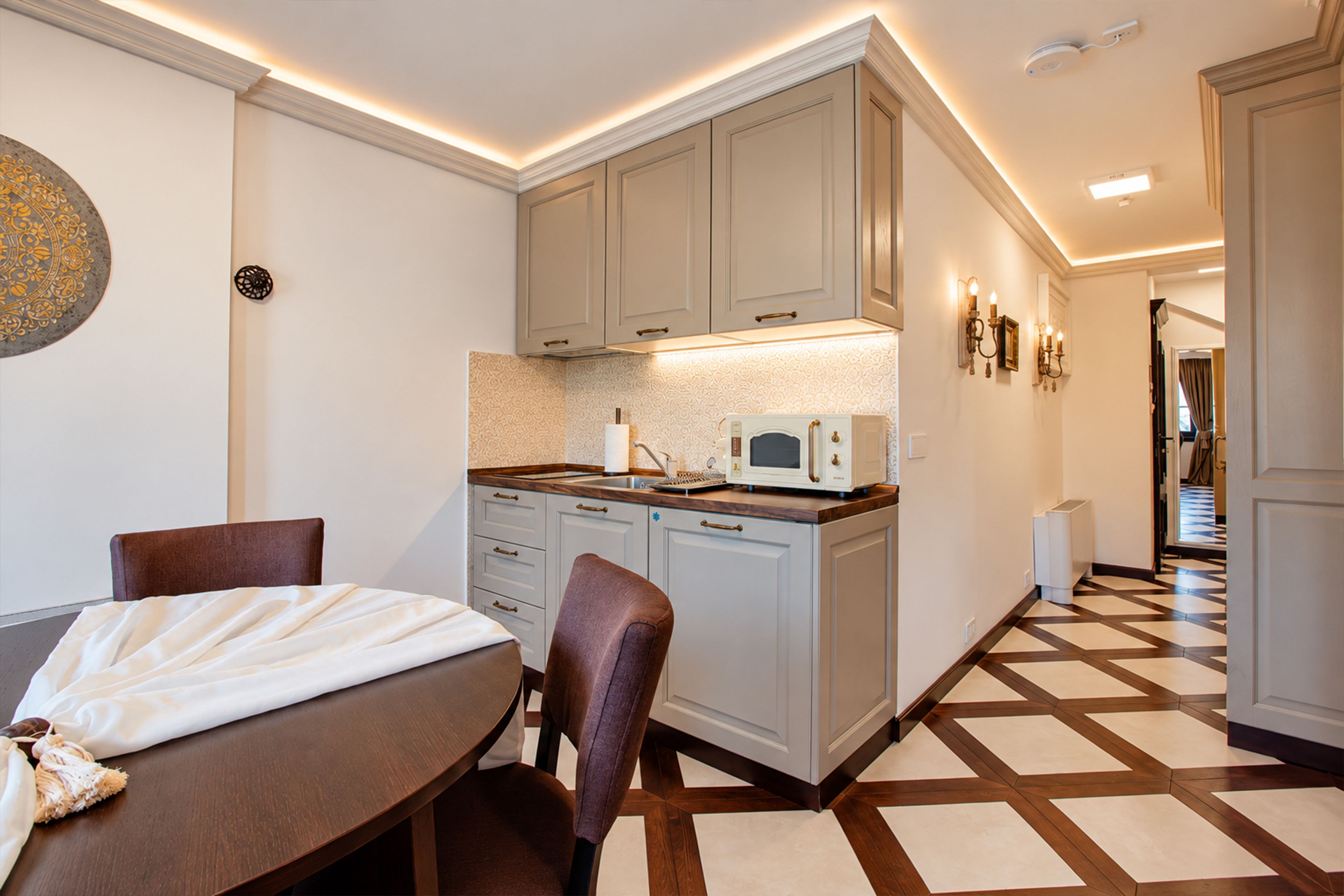 Una cocina compacta con microondas, un lavamanos pequeño y una zona de comedor con mesa y sillas.