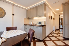 A compact kitchen with a microwave, a small sink, and a dining area with a table and chairs. - Villa Amfitea (Ohrid)