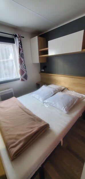 Ein Zimmer mit einem Bett, einem Vorhangfenster, einem Nachttisch und einem Kleiderschrank.