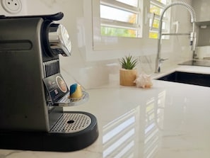 A coffee machine on a countertop with a small plant and decorative item nearby. - Villa Azura – 4 Bedrooms, Infinity Pool, Spa & Surf | Le Helleux (Sainte-Anne)