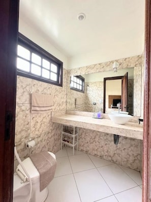 A bathroom with a marble wall, a large mirror, a sink, and a toilet. - Apartment in Taperapua with pool on Rua Arena Axe Moi (Porto Seguro)