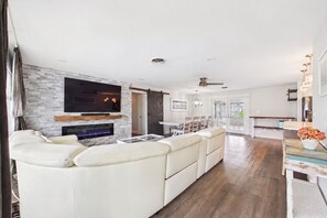 A modern living room with a fireplace, a flat-screen TV, and a dining area with a table and chairs. - Fantastic 4-bedroom house 1 block from ocean in charming Satellite Beach (Satellite Beach)