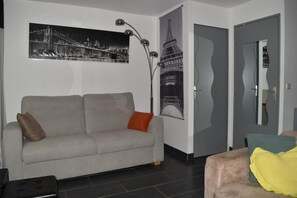 A living room with a sofa, a coffee table, and a wall-mounted lamp. - Spacious studio apartment with a view of the docks, a terrace, an elevator, and parking (Sète)