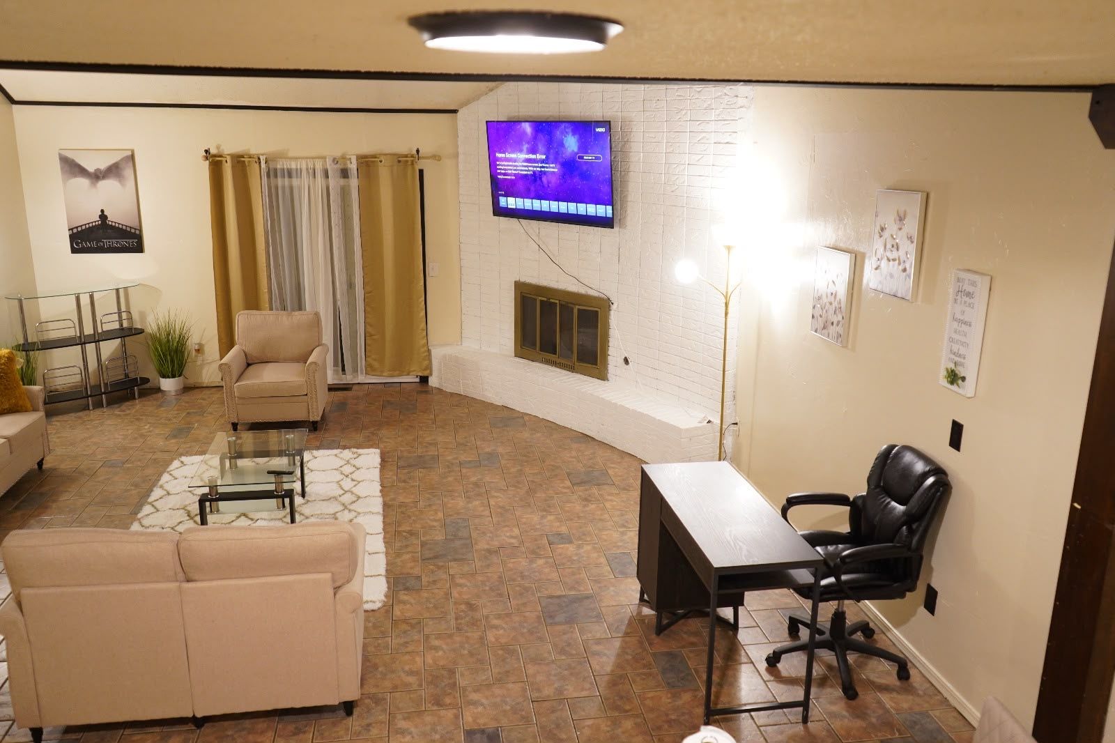 A living room with a television, a fireplace, a sofa, a coffee table, and a desk with a chair.