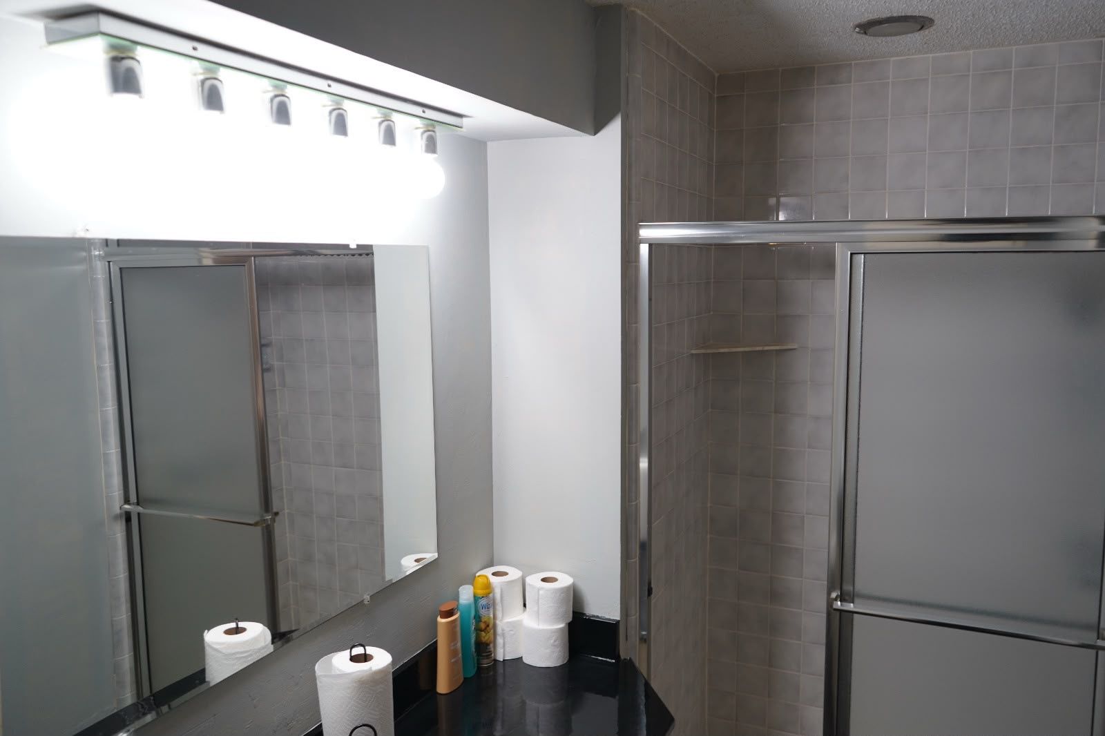 A restroom with a mirror, toilet paper, and a hand dryer.