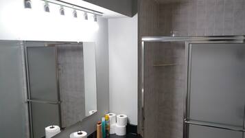A restroom with a mirror, toilet paper, and a hand dryer.
