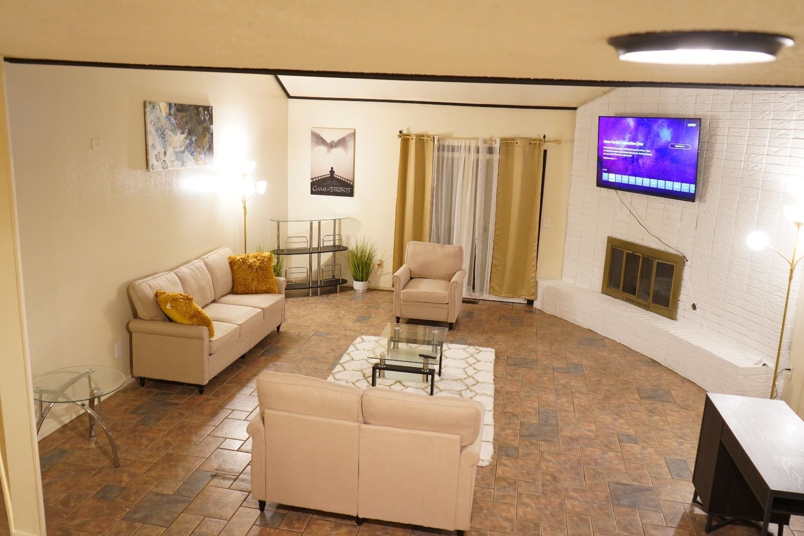 A living room with a sofa, armchair, coffee table, and a TV mounted on a brick wall.