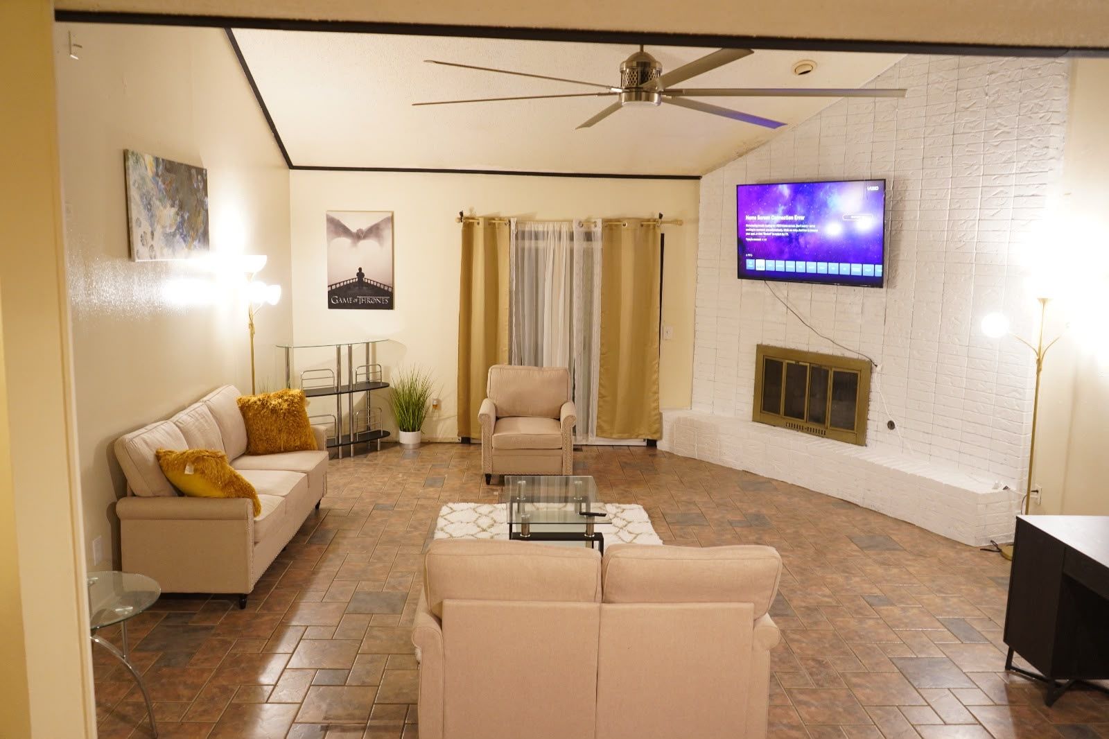 A living room with a sofa, armchair, coffee table, and a flat-screen TV mounted on the wall.