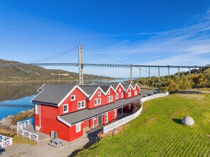 A red building with a dock, a white fence, and a bridge in the background. - Tjeldsund rorbu by the sea (Tjeldsund)